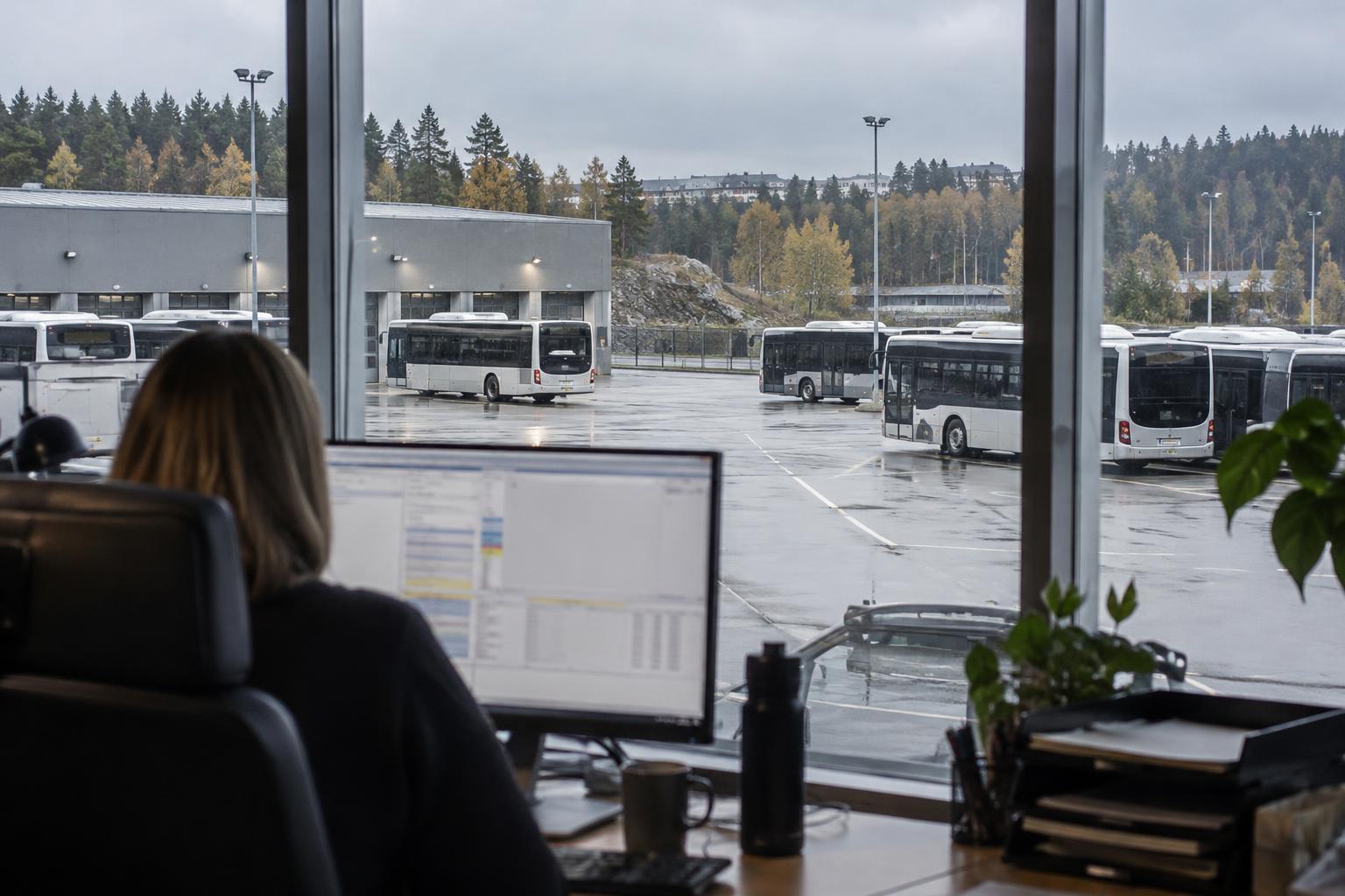 Illustrativ bild av en arbetsplats på ett trafikkontor med bussar utanför fönstret.